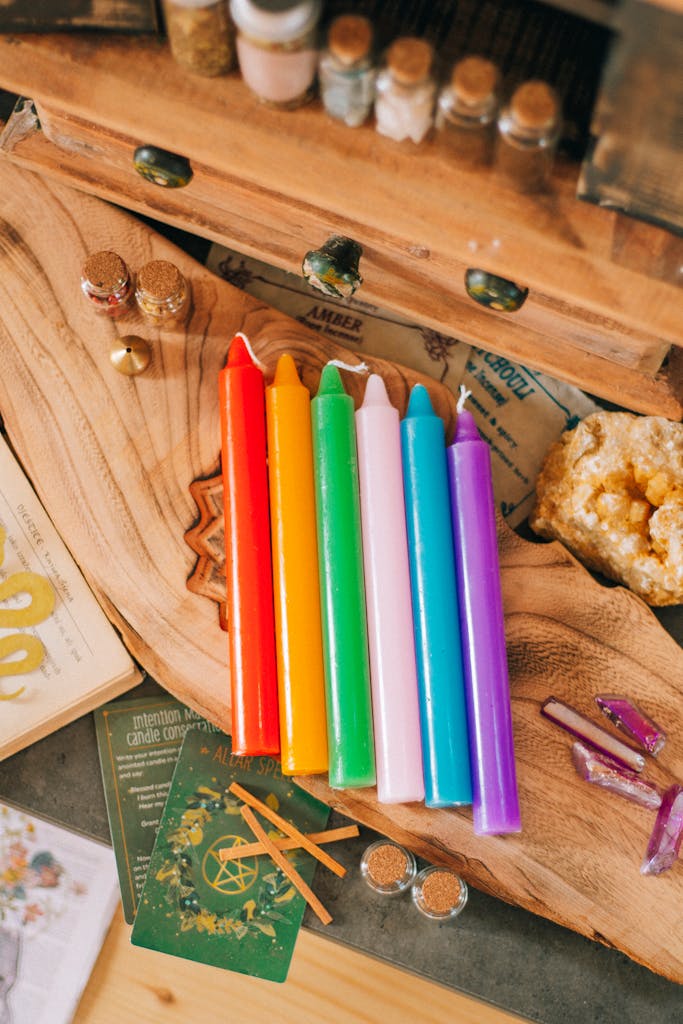 Colorful set of candles on a crafted desk surrounded by artistic decor, perfect for creative photography.