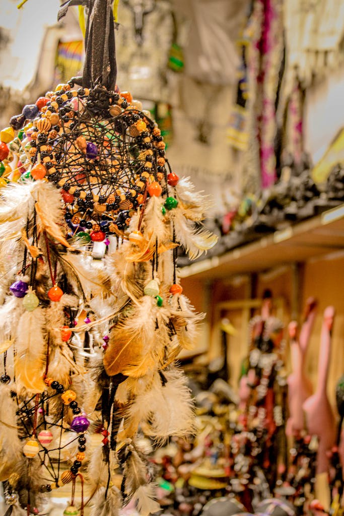 Vibrant dreamcatcher with feathers and beads, hanging in a craft shop setting.