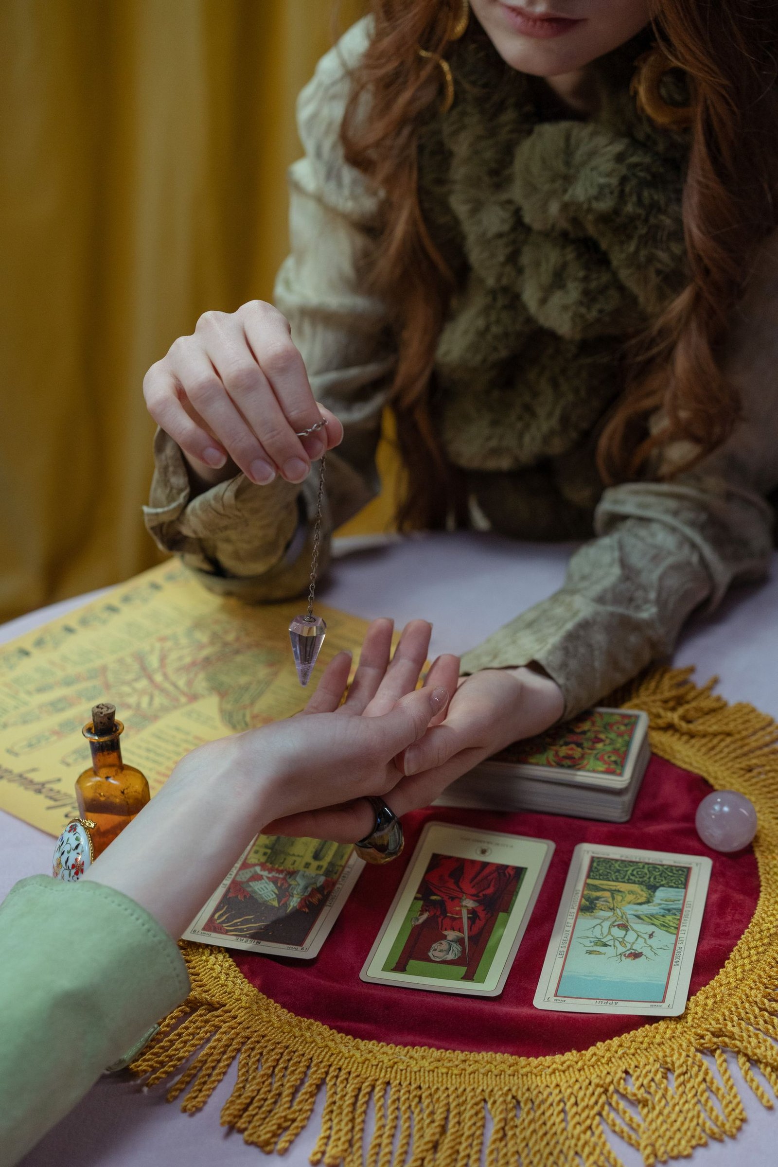 A mystical tarot card reading session indoors with a crystal pendulum.