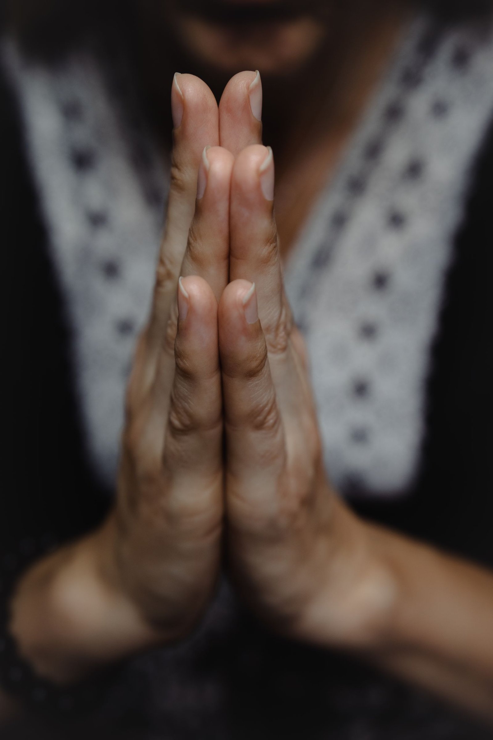 Close-up of hands in a prayer position set against a blurred background, evoking peace and spirituality.